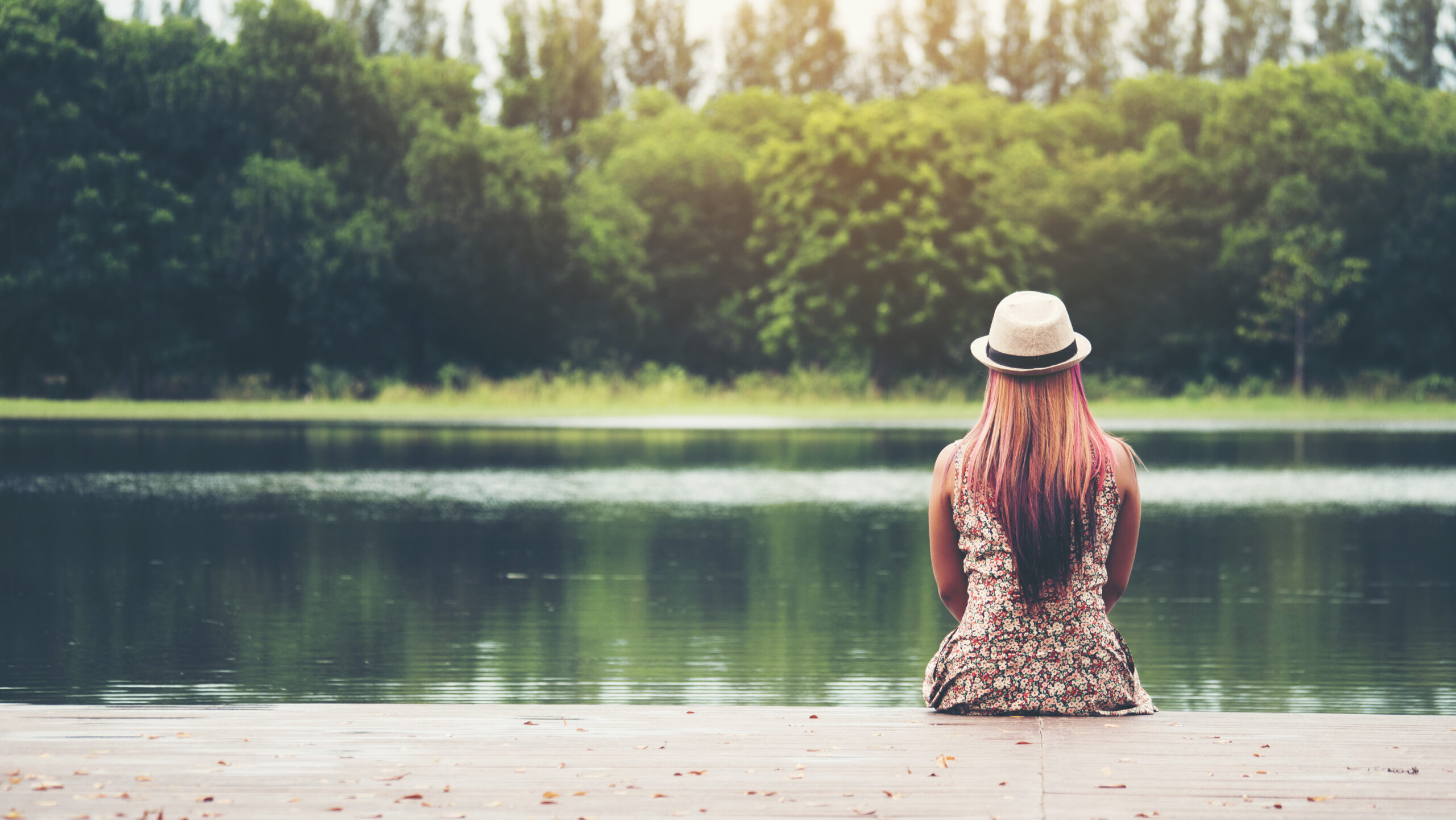young woman sitting on pier and looking at the river.